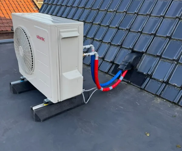 Airco buitenunit geplaatst op een plat dak van een woning